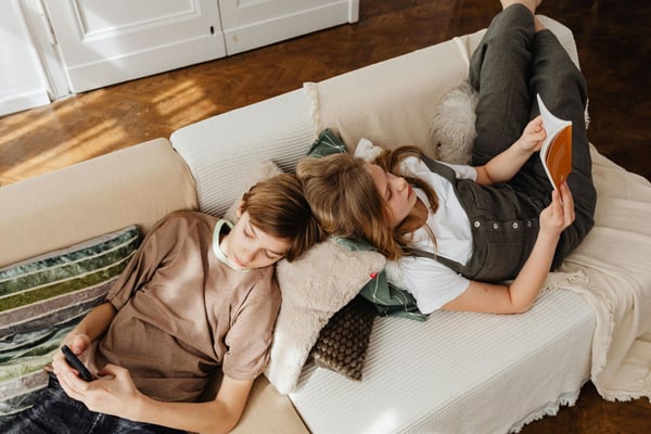 girl-and-boy-lying-on-couch-reading