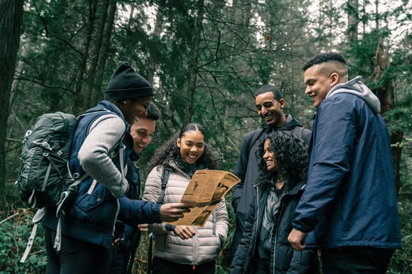 six-friends-look-at-newspaper-in-forest