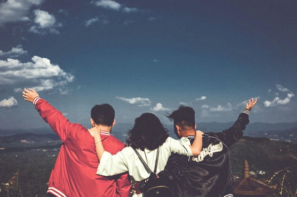 three friends arms raised in nature